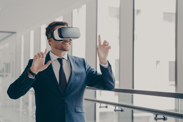 Apuesto hombre de negocios sonriente en auriculares vr usando tecnologías innovadoras para los negocios en el trabajo