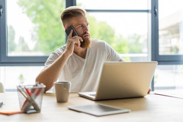 Apuesto hombre de negocios trabajando con ordenador portátil en la oficina.