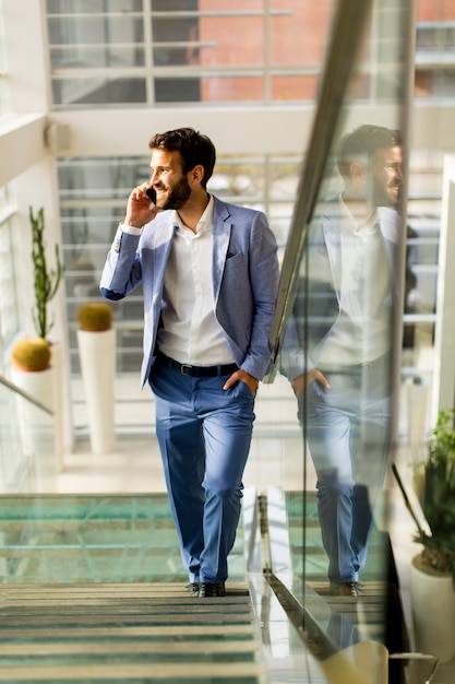 Apuesto hombre de negocios en traje hablando por teléfono en la oficina