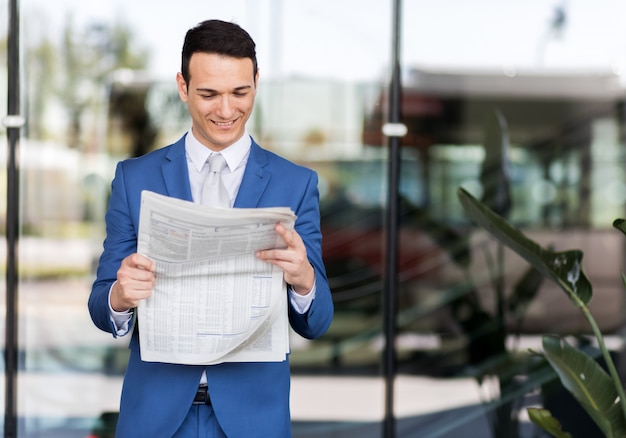 Apuesto hombre de negocios en traje leyendo el periódico