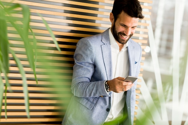 Apuesto hombre de negocios en traje sosteniendo el teléfono en la oficina