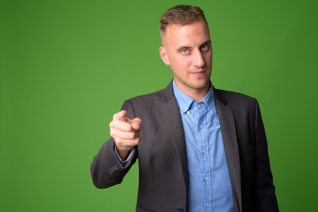 Apuesto hombre de negocios vistiendo traje contra la pared verde