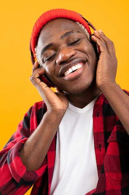 Apuesto hombre negro americano sonriente disfrutando de la música con auriculares de cerca