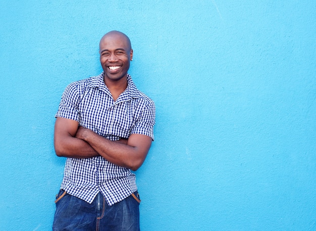 Apuesto hombre negro sonriendo con los brazos cruzados