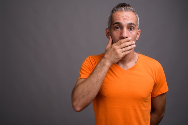 Apuesto hombre persa con cabello gris con camiseta naranja