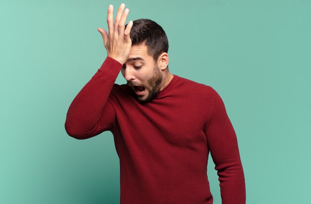 Apuesto hombre rubio adulto levantando la palma de la mano a la frente pensando Ups, después de cometer un error estúpido o recordar, sentirse tonto