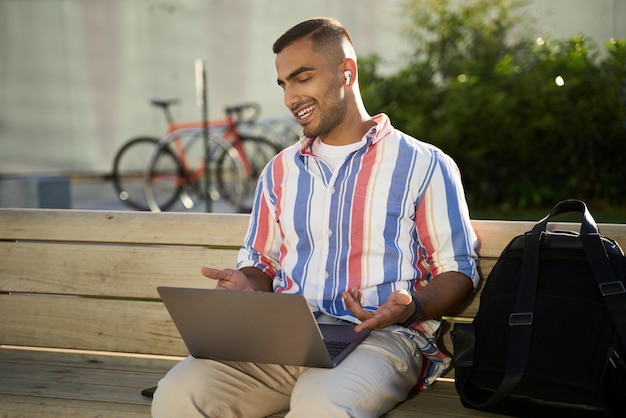 Apuesto hombre sonriente del Medio Oriente usando una computadora portátil con video. Freelancer trabajando en línea