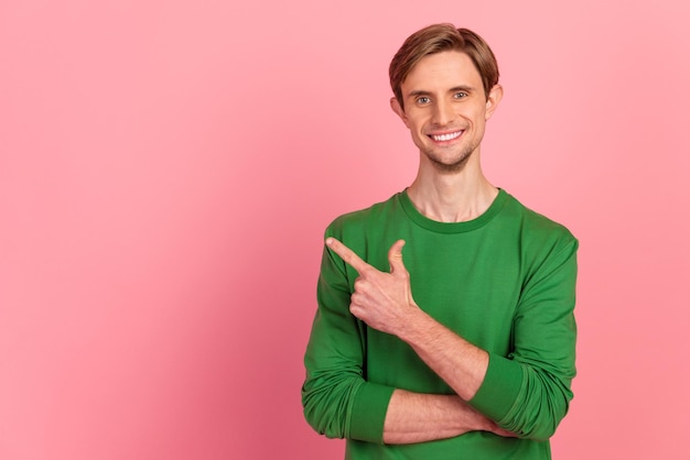 Un apuesto hombre sonriente señalando el espacio vacío elige una opción aislada en un fondo de color pastel