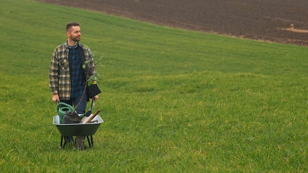 El apuesto jardinero caminando con una carretilla por el campo