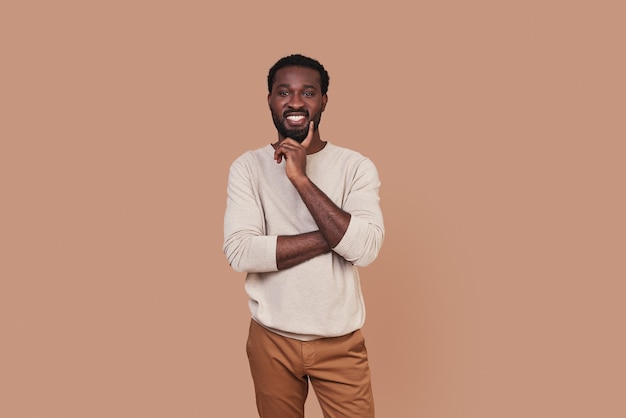 Apuesto joven africano en ropa casual mirando a cámara y sonriendo