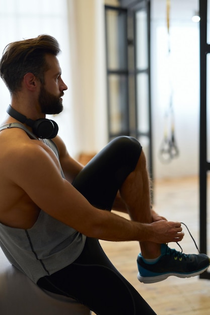 Apuesto joven atando sus zapatillas antes de entrenar