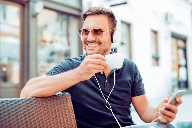 Apuesto joven con auriculares blancos afuera