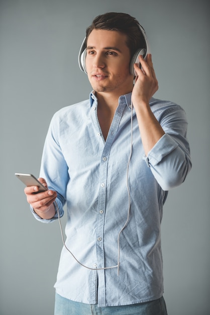 Apuesto joven en auriculares está escuchando música