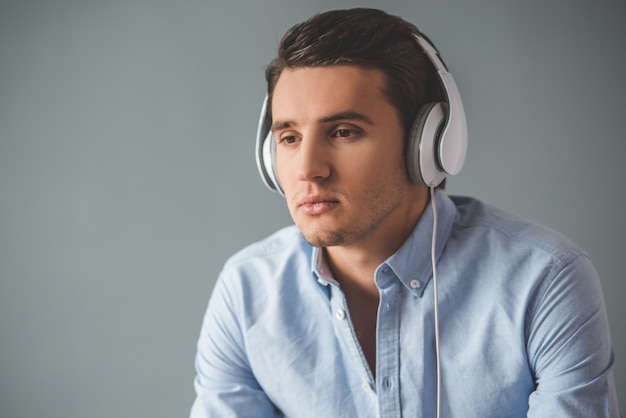 Apuesto joven en auriculares está escuchando música.