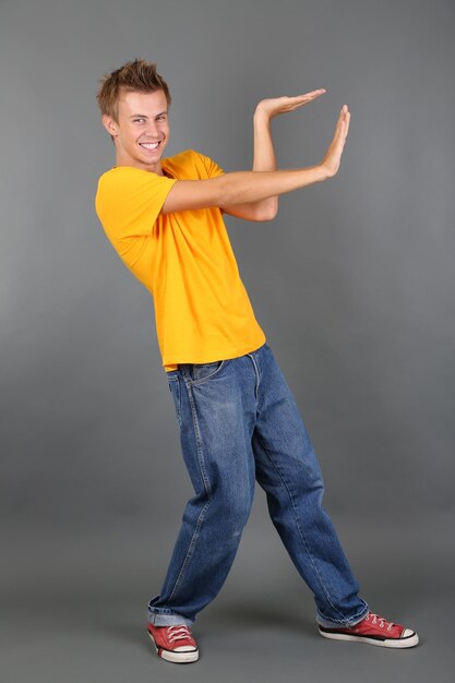 Foto apuesto joven bailando sobre fondo gris