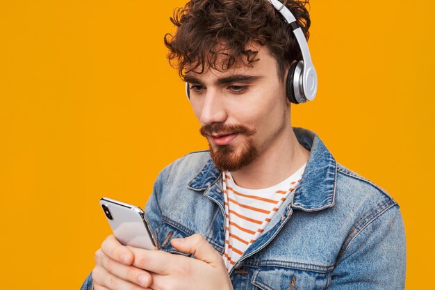 Apuesto joven barbudo escuchando música con auriculares aislados