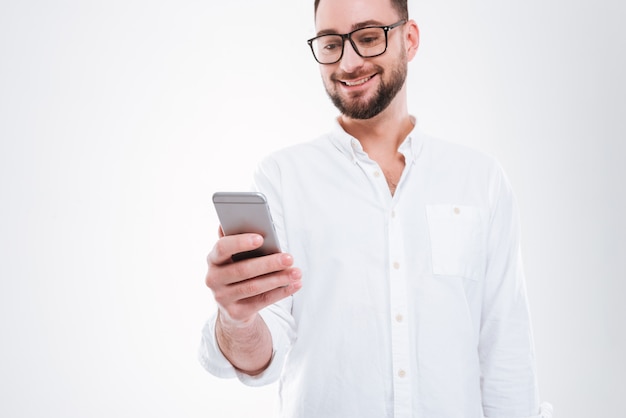 Apuesto joven barbudo feliz chateando por teléfono