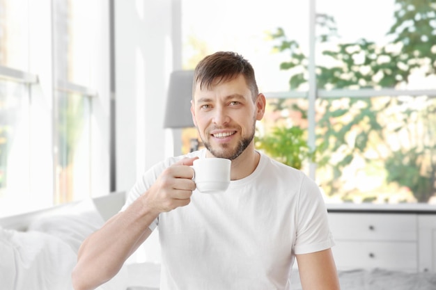 Apuesto joven bebiendo café en casa