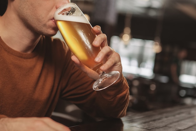 Apuesto joven bebiendo cerveza en el bar