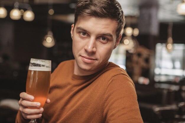 Apuesto joven bebiendo cerveza en el bar