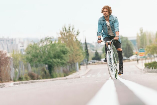 Apuesto joven en bicicleta en la ciudad. Concepto de bicicleta