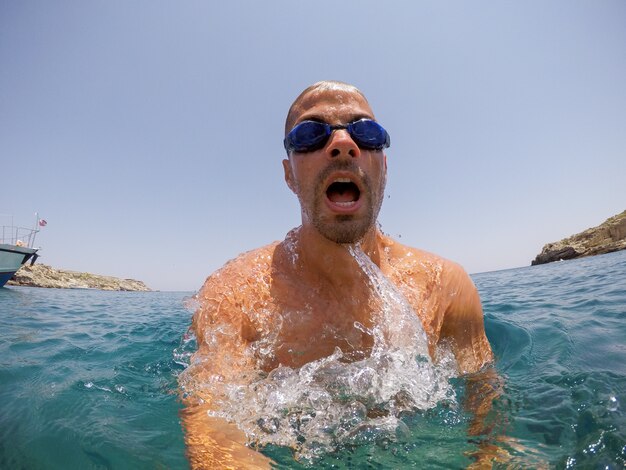 Apuesto joven buzo activo divirtiéndose en el exótico mar durante el verano.