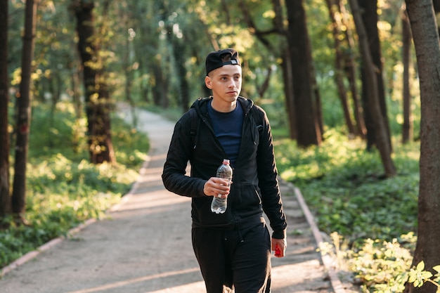 Apuesto joven caminando con botella de plástico