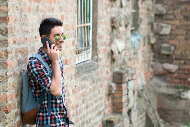 Apuesto joven caminando con teléfono móvil y mochila