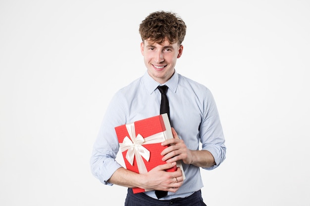 Apuesto joven en camisa y corbata sosteniendo una caja de regalo.