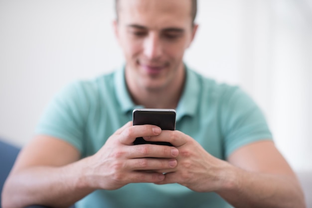 Apuesto joven casual usando un teléfono móvil en casa de lujo