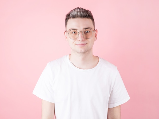 Apuesto joven caucásico sonriendo a la cámara sobre fondo rosa