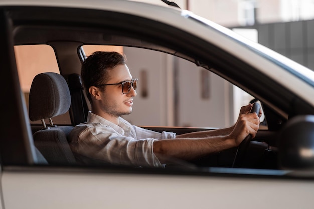 Apuesto joven en un coche blanco al volante