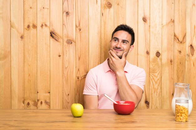 Apuesto joven en una cocina desayunando pensando en una idea