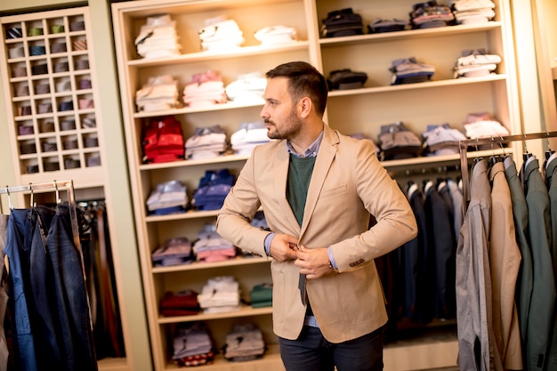 Apuesto joven comprando ropa en la tienda de moda