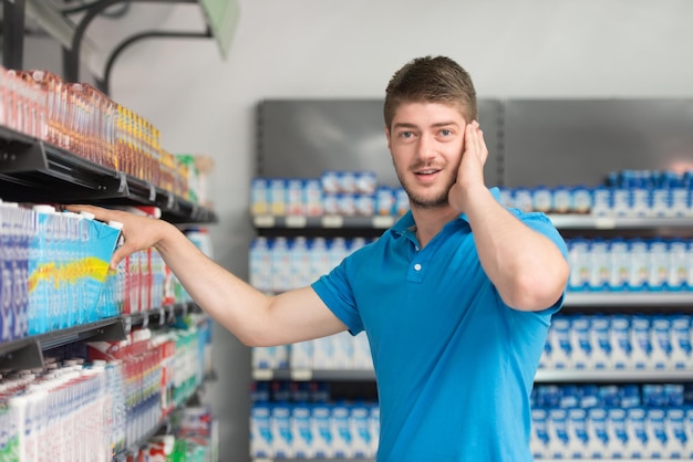 Apuesto joven para compras de leche y queso en el departamento de producción de una tienda de abarrotes Supermercado Shallow Deep Of Field