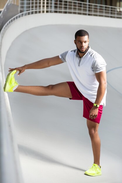 Foto apuesto joven deportivo pensativo haciendo ejercicio de pierna