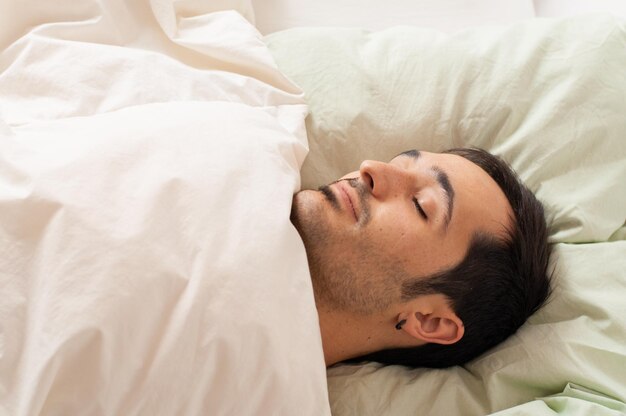 Foto apuesto joven durmiendo durante la mañana