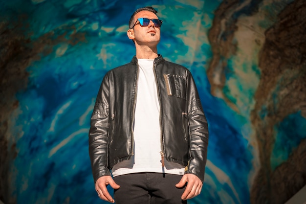 Foto apuesto joven elegante con traje de cuero y gafas de sol