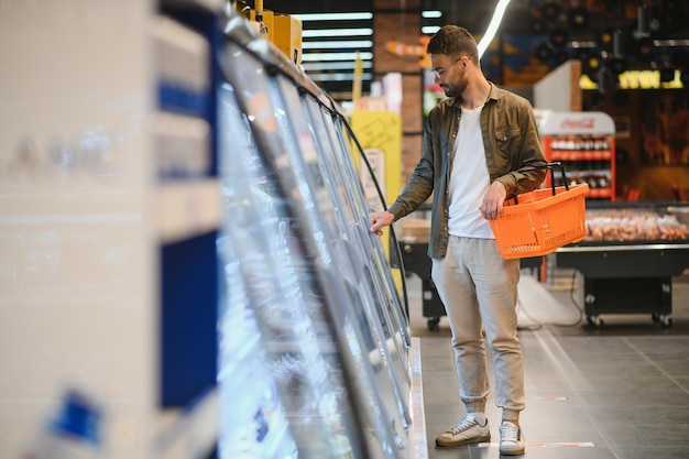 Apuesto joven eligiendo comida en el supermercado