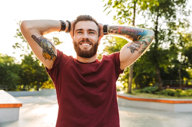 Foto apuesto joven emocionado vestido con ropa casual, pasar tiempo en el parque, posando