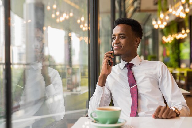 Apuesto joven empresario africano en cafetería restaurante