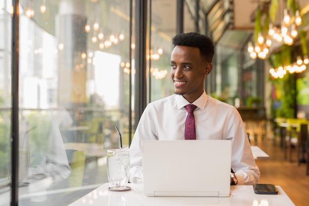 Apuesto joven empresario africano en cafetería restaurante