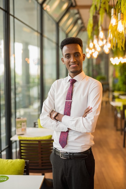 Apuesto joven empresario africano en cafetería restaurante