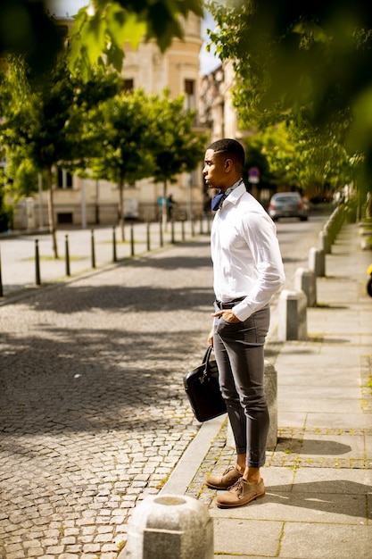 Apuesto joven empresario afroamericano esperando un taxi en la calle