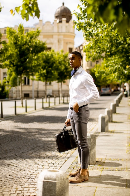 Apuesto joven empresario afroamericano esperando un taxi en una calle