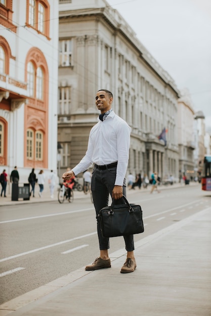 Foto apuesto joven empresario afroamericano esperando un taxi en una calle