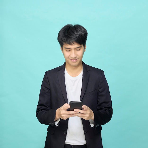 Apuesto joven empresario asiático texting Work, sosteniendo el teléfono inteligente, manténgase conectado mediante teléfono móvil, internet, red social de desplazamiento en línea,