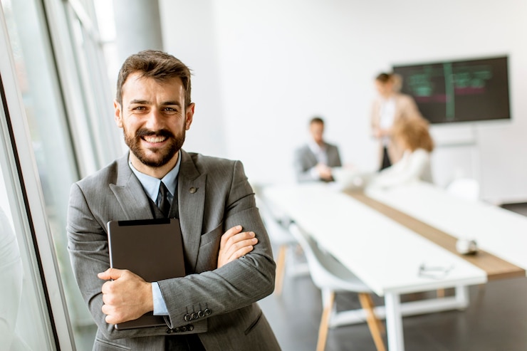 Foto apuesto joven empresario moderno con tableta digital en la oficina