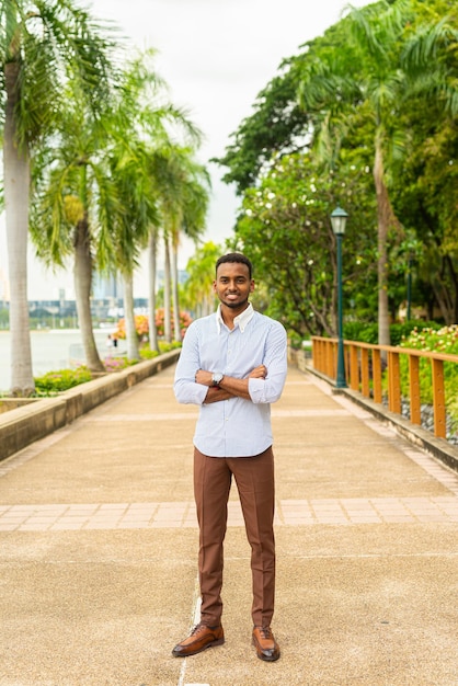 Apuesto joven empresario negro en el parque al aire libre durante el verano