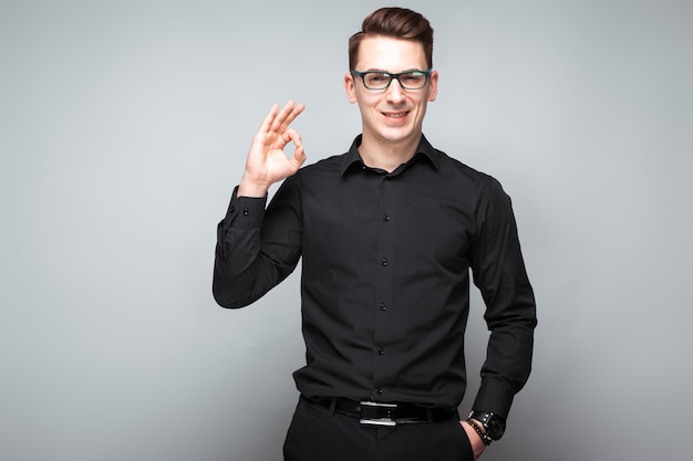 Apuesto joven empresario en reloj costoso, gafas negras y camisa negra